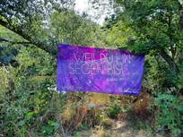 blaues Stoffbanner an Ästen aufgehängt mit Aufschrift "Weil du ein Segen bist #deine Taufe"