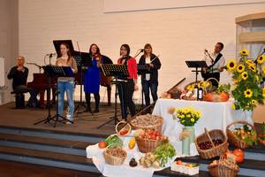 Quelle: Hosanna Gemeinde Lobpreisband auf der Bühne neben den Körben mit Obst und Gemüse für Erntedank